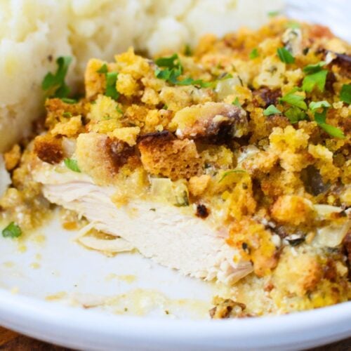 Sliced slow cooker chicken breast with stuffing and mashed potatoes on white plate, ready to serve