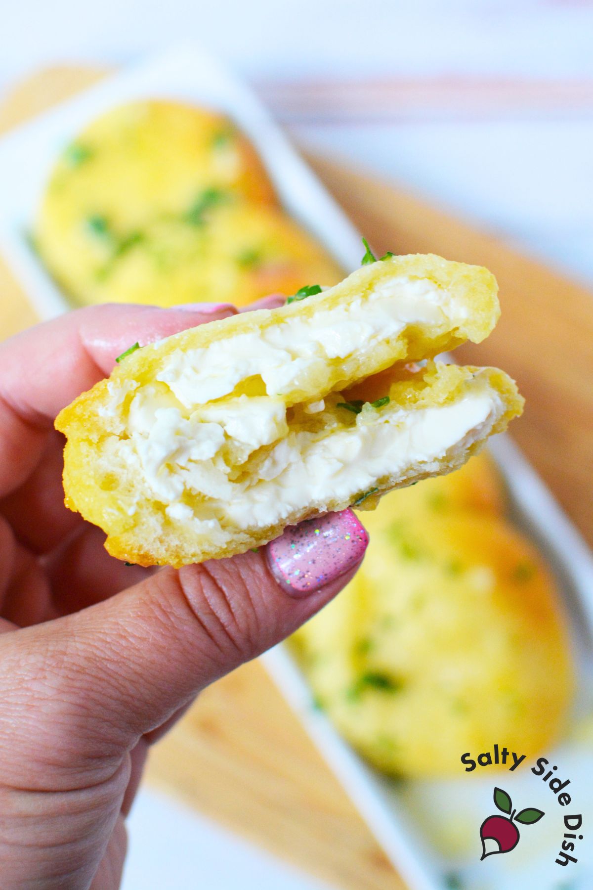 Close-up of a golden garlic bread disk filled with warm cream cheese, sliced open to show the creamy center