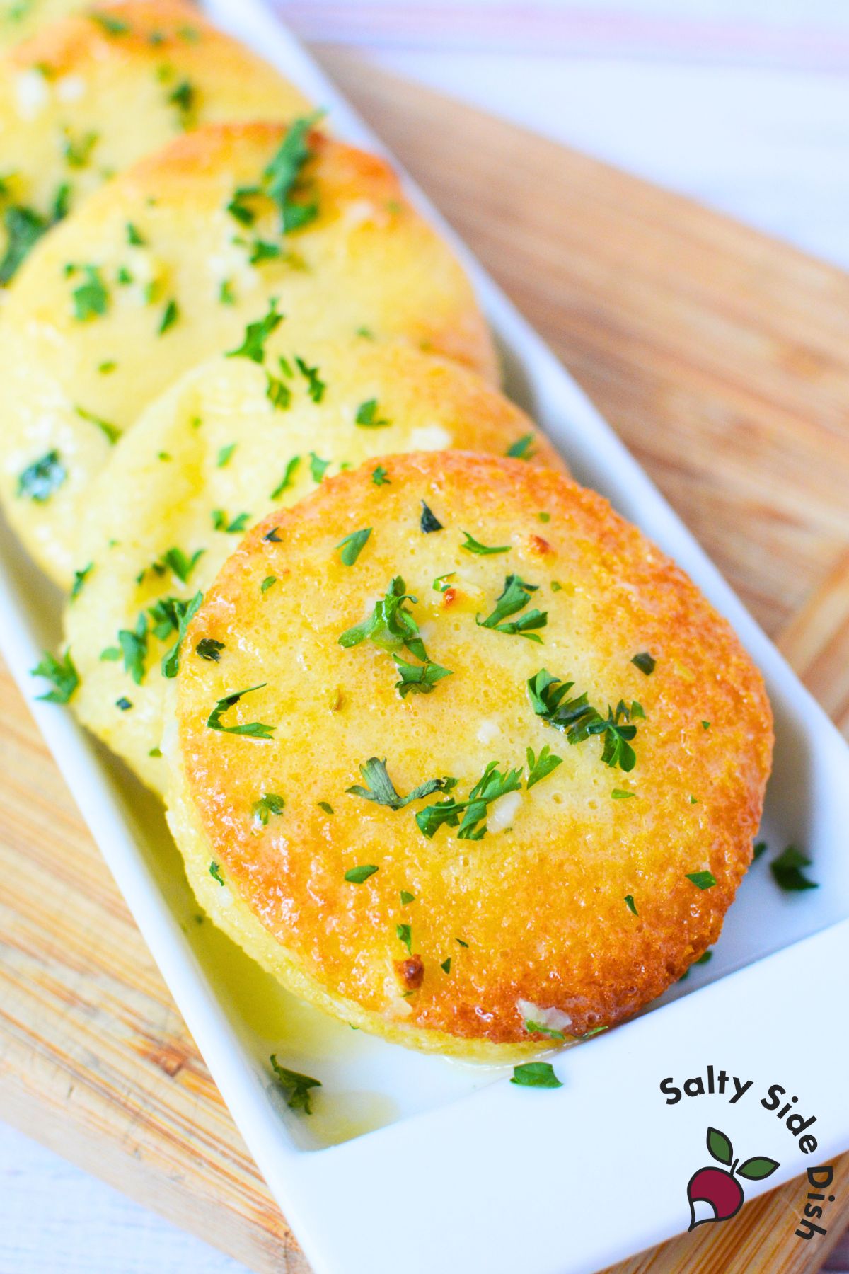 Plated garlic cream cheese disks topped with chopped parsley and baked to a golden brown