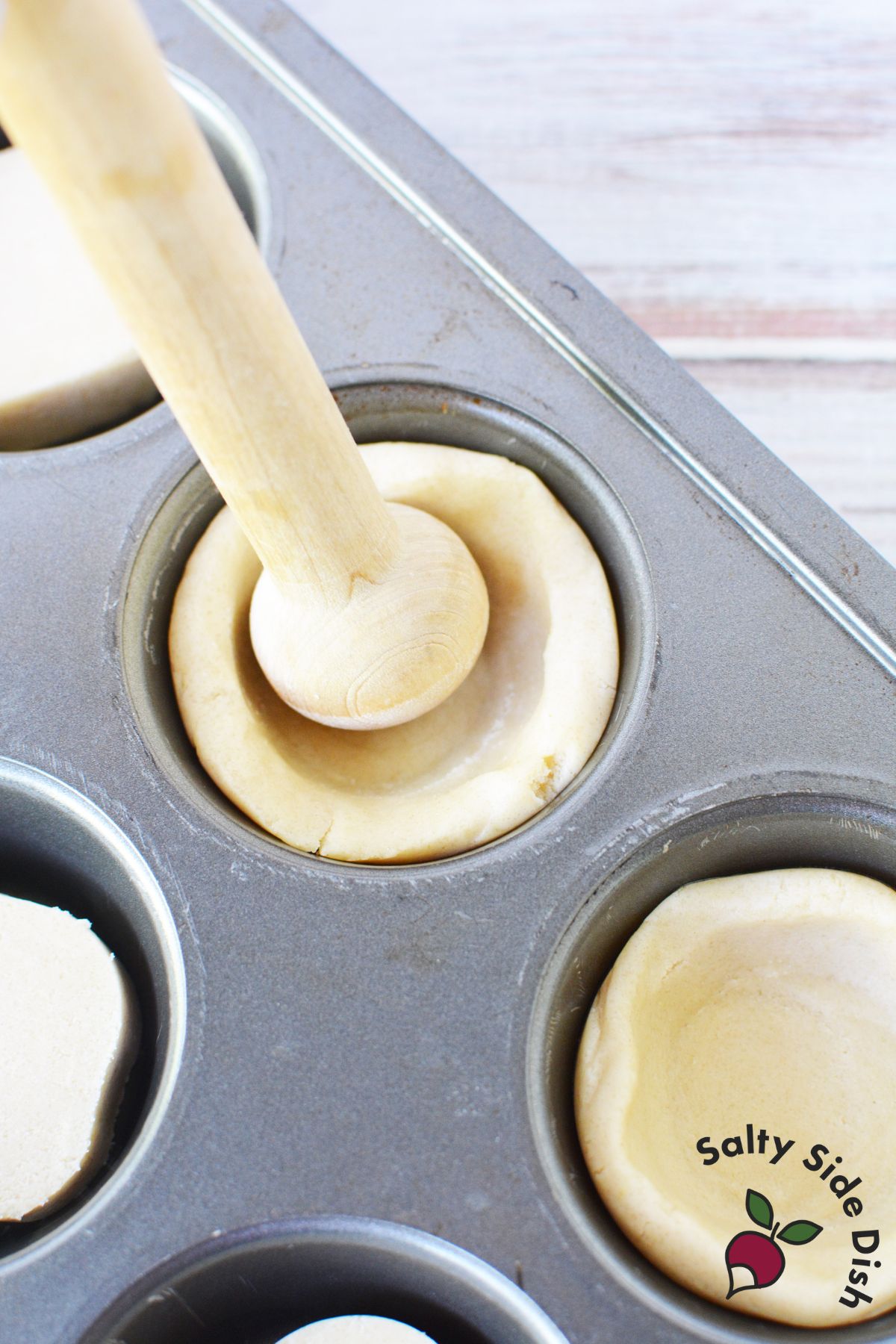 Pressing sugar cookie dough into muffin tins to form cookie cups using a tart shaper