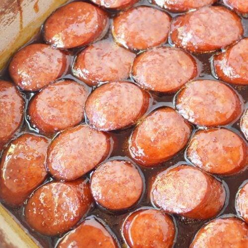 Smoked sausage slices coated in caramelized brown sugar BBQ glaze, hot from the oven