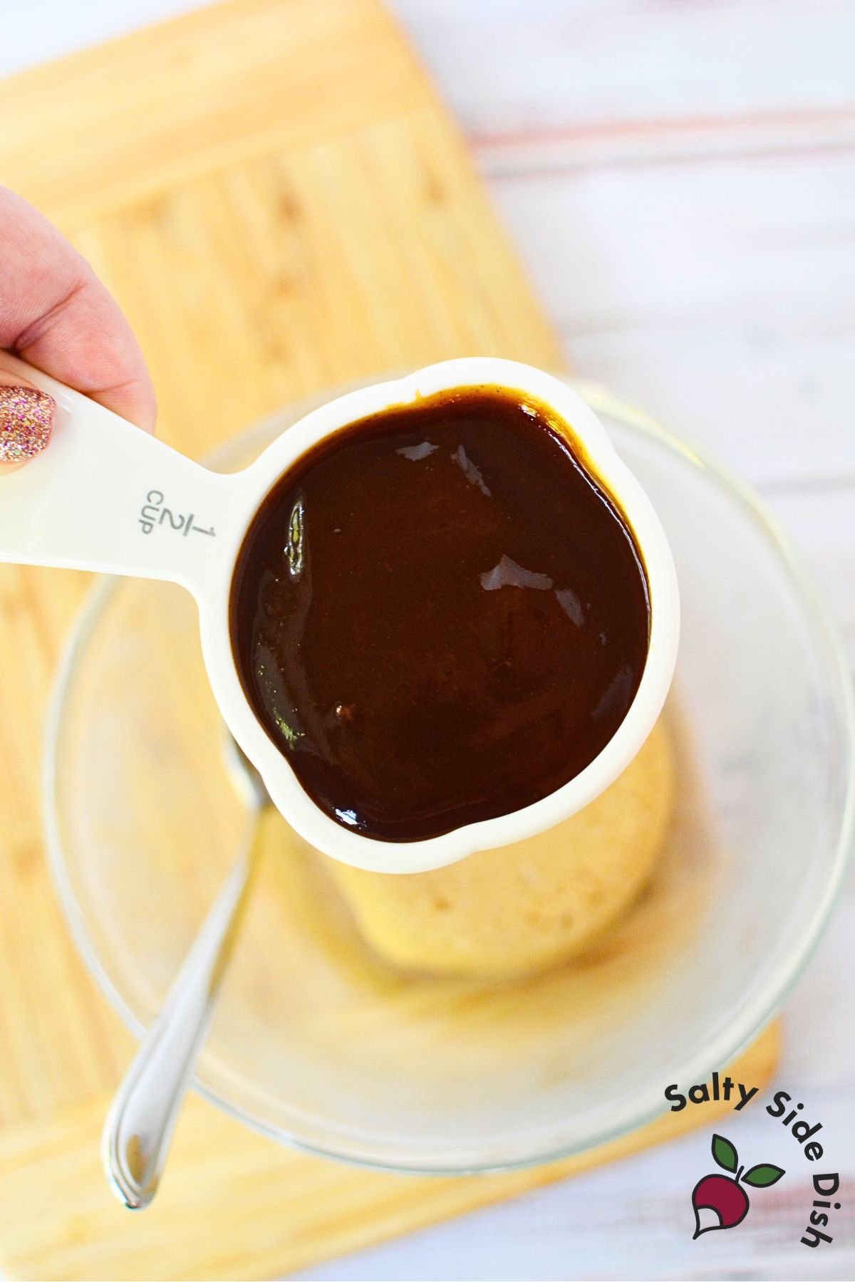 Measuring cup of thick BBQ sauce poured over brown sugar to make sweet sausage glaze
