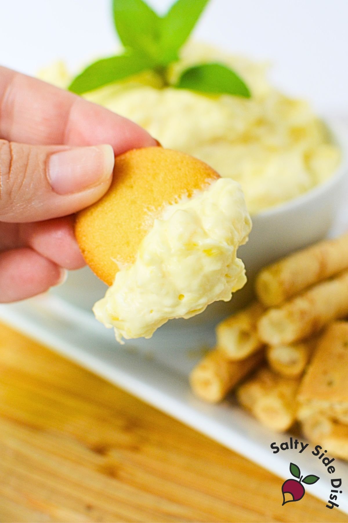 Vanilla wafer dipped into pineapple cream cheese dip, showing thick and creamy texture