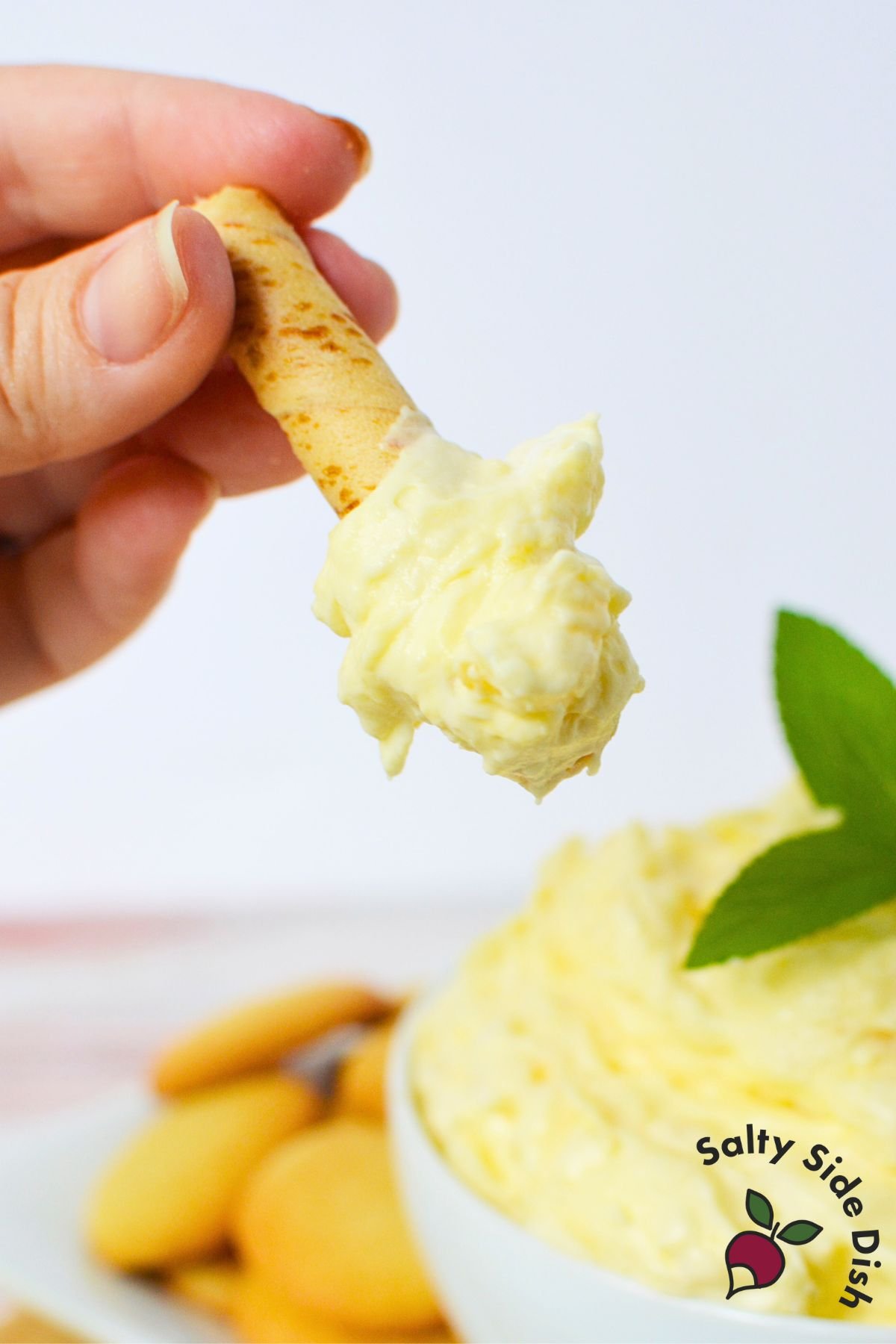 Spoonable pineapple pudding dip served on a vanilla wafer stick, perfect for parties or snacks