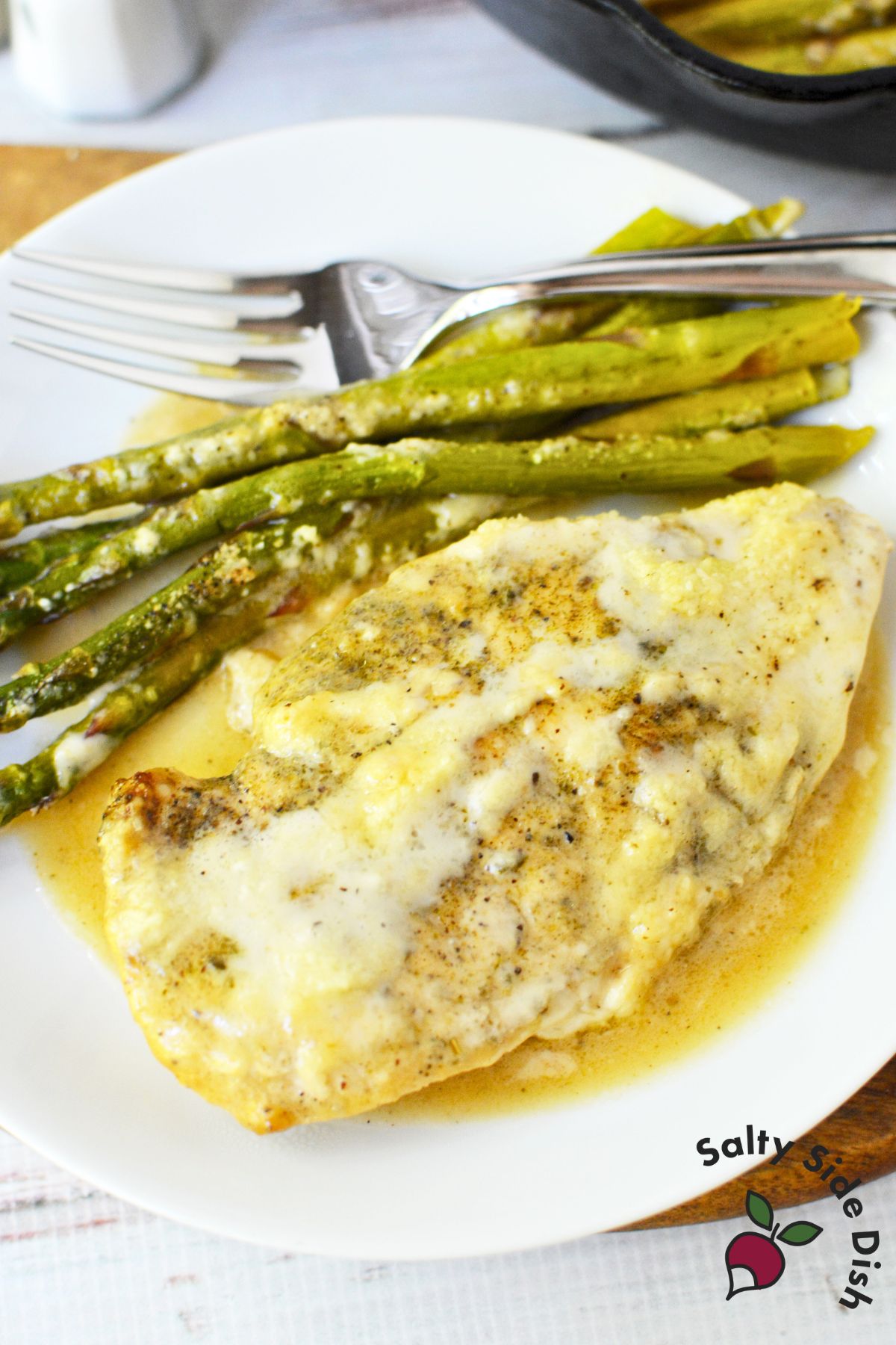 Cast iron Caesar chicken skillet dinner with asparagus served on a white plate