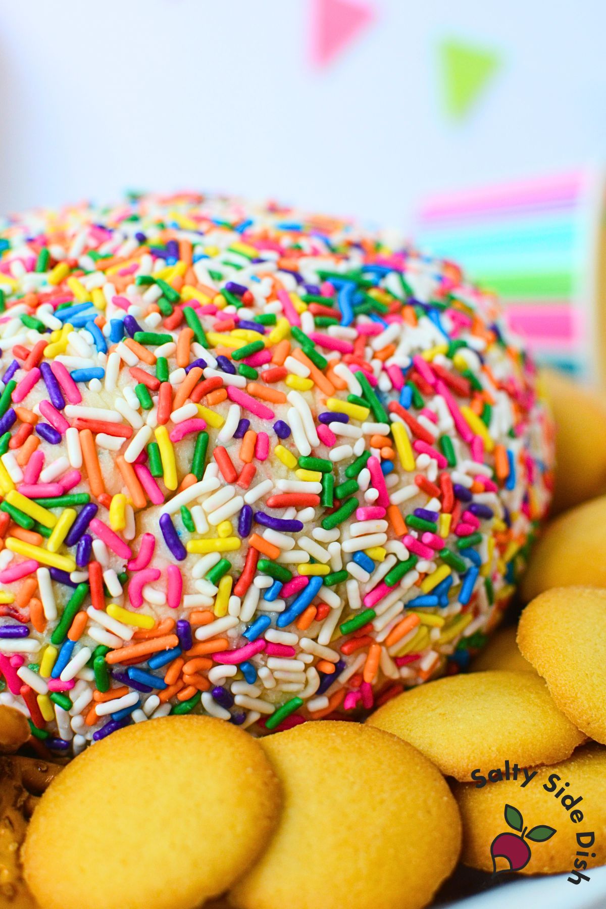 Birthday cake cheese ball covered in rainbow sprinkles served with Nilla wafers and pretzels.