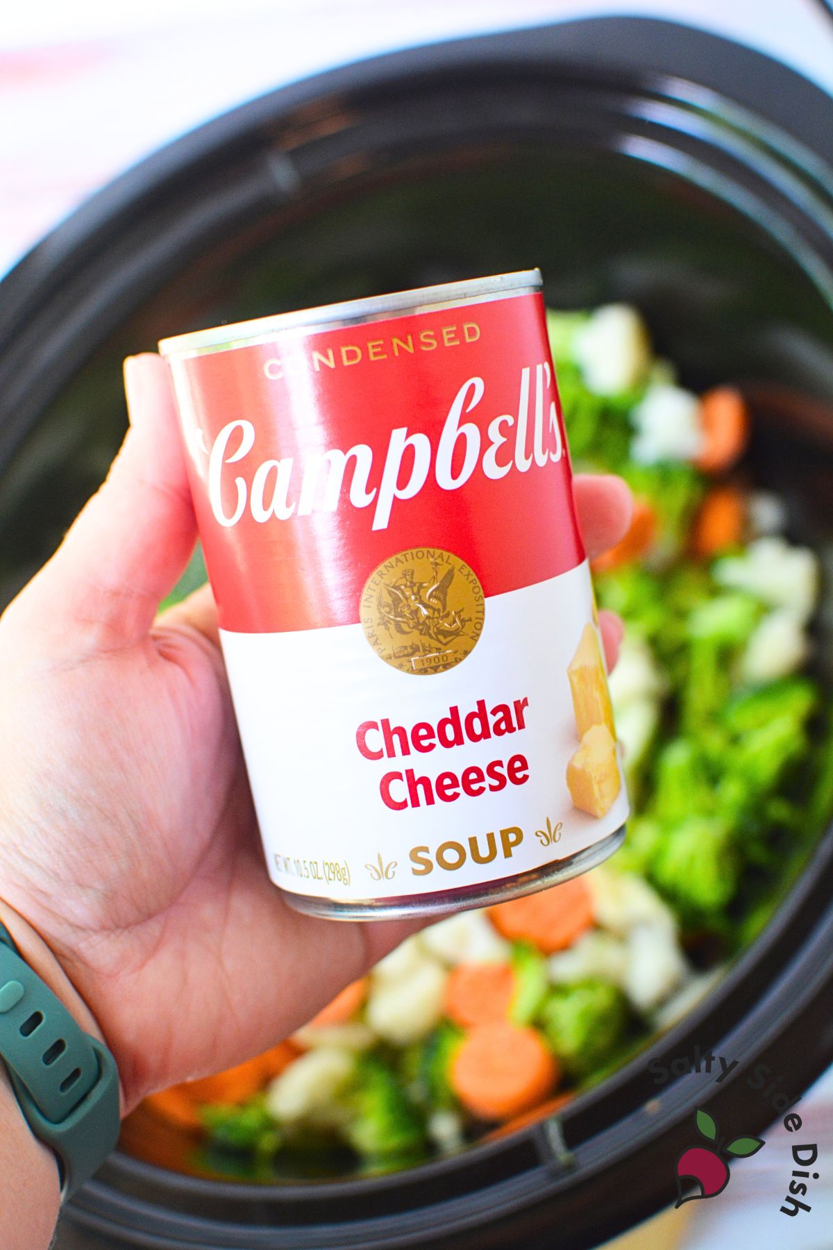 Campbell’s Cheddar Cheese condensed soup held over slow cooker with vegetables