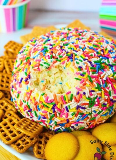 Funfetti dessert cheese ball rolled in colorful sprinkles with graham crackers and pretzels for dipping.