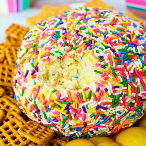 Funfetti dessert cheese ball rolled in colorful sprinkles with graham crackers and pretzels for dipping.