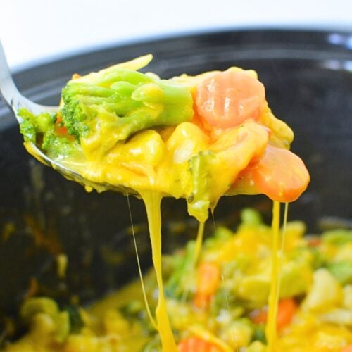 Frozen California medley vegetables (broccoli, carrots, cauliflower) in a spoon.