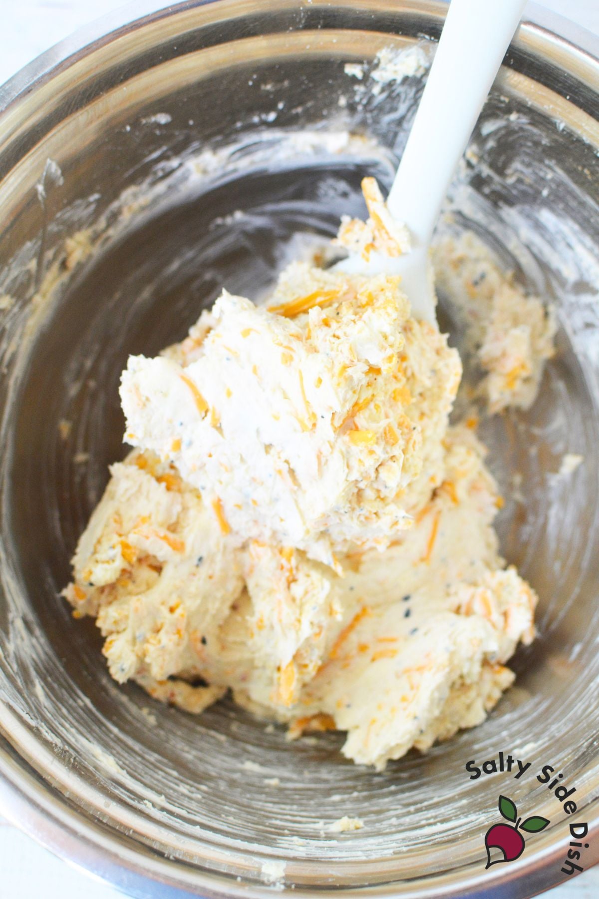 Cream cheese mixture with cheddar and seasoning being mixed for everything bagel cheese ball