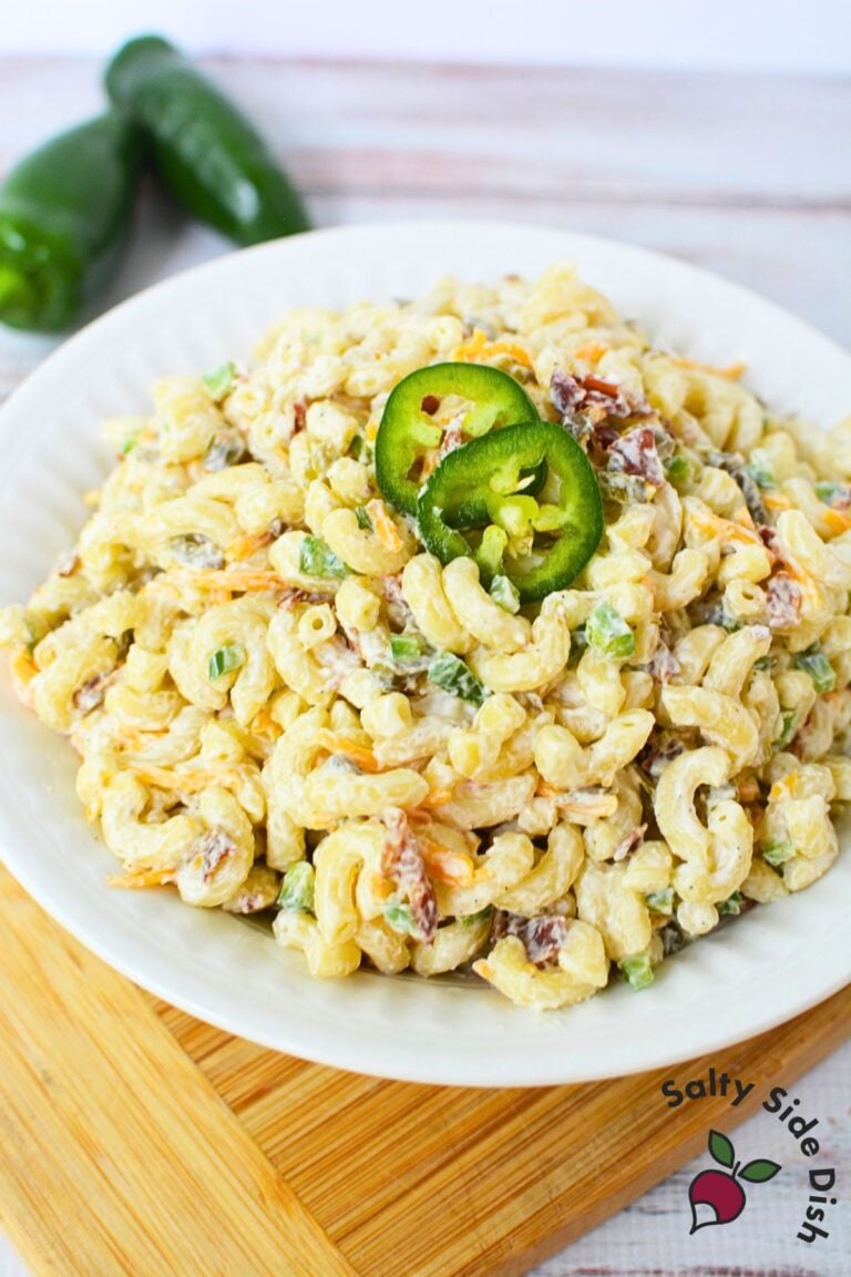 Mixing bowl with elbow macaroni, shredded cheddar cheese, crumbled bacon, and diced jalapenos for jalapeno popper pasta salad