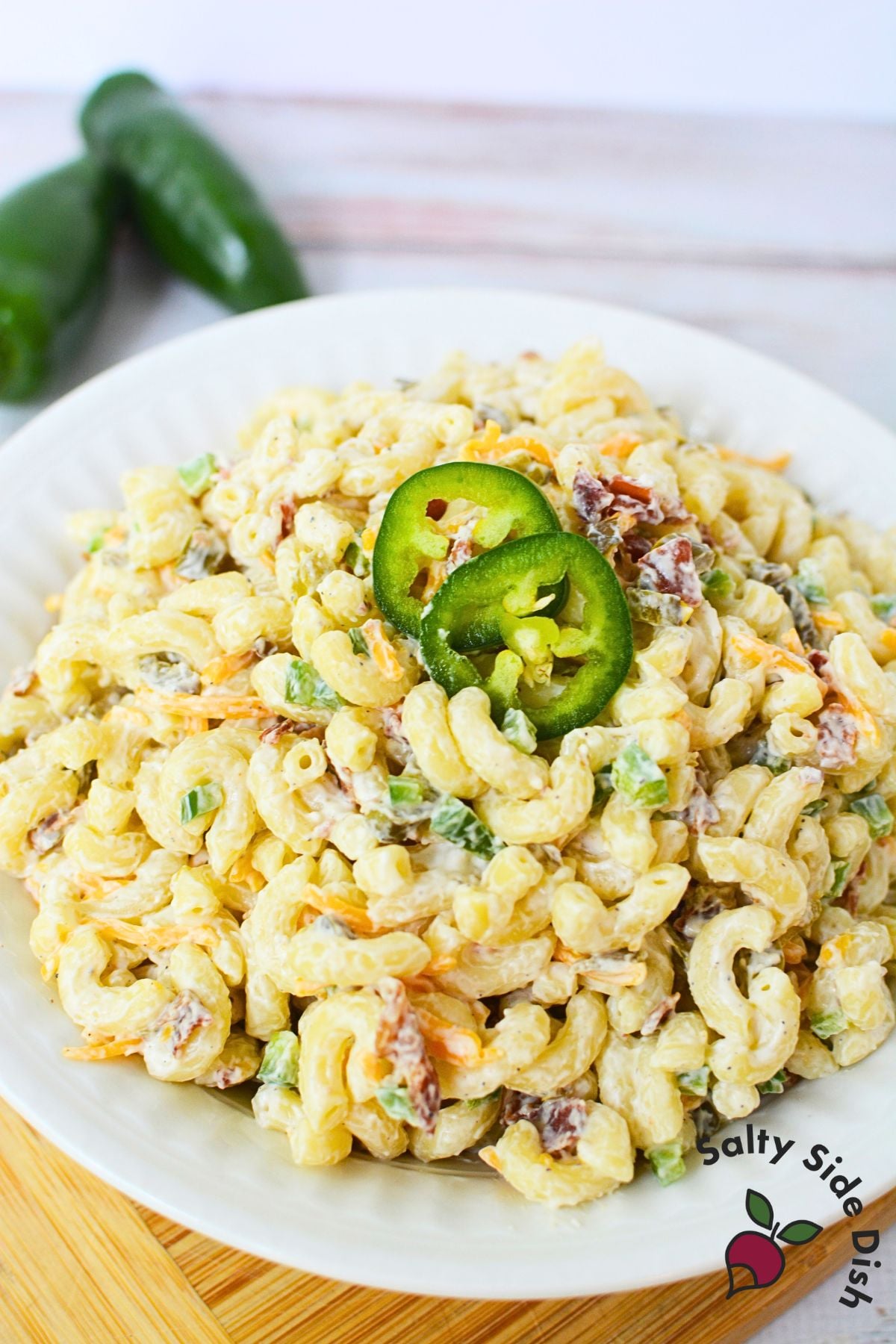 Creamy jalapeno popper pasta salad in a white bowl topped with sliced jalapenos