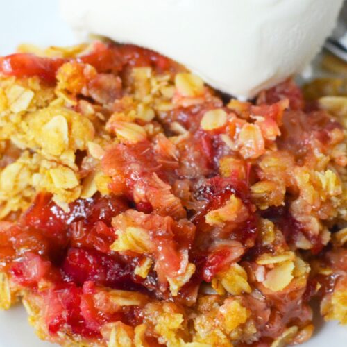 tart rhubarb crisp on a plate with vanilla ice cream.