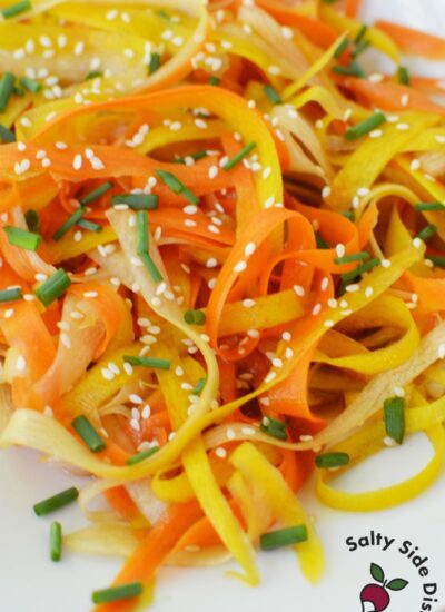 Rainbow shaved carrot salad served with sesame soy dressing and chopsticks resting on top