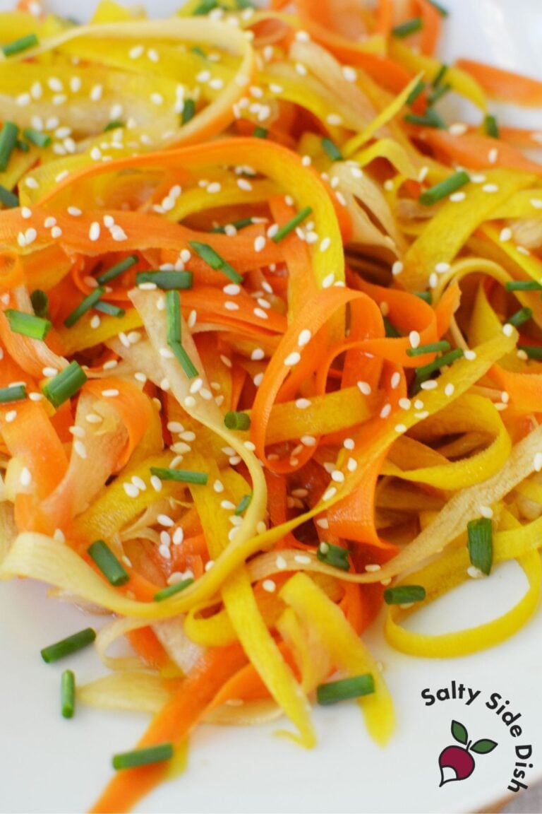 Rainbow shaved carrot salad served with sesame soy dressing and chopsticks resting on top