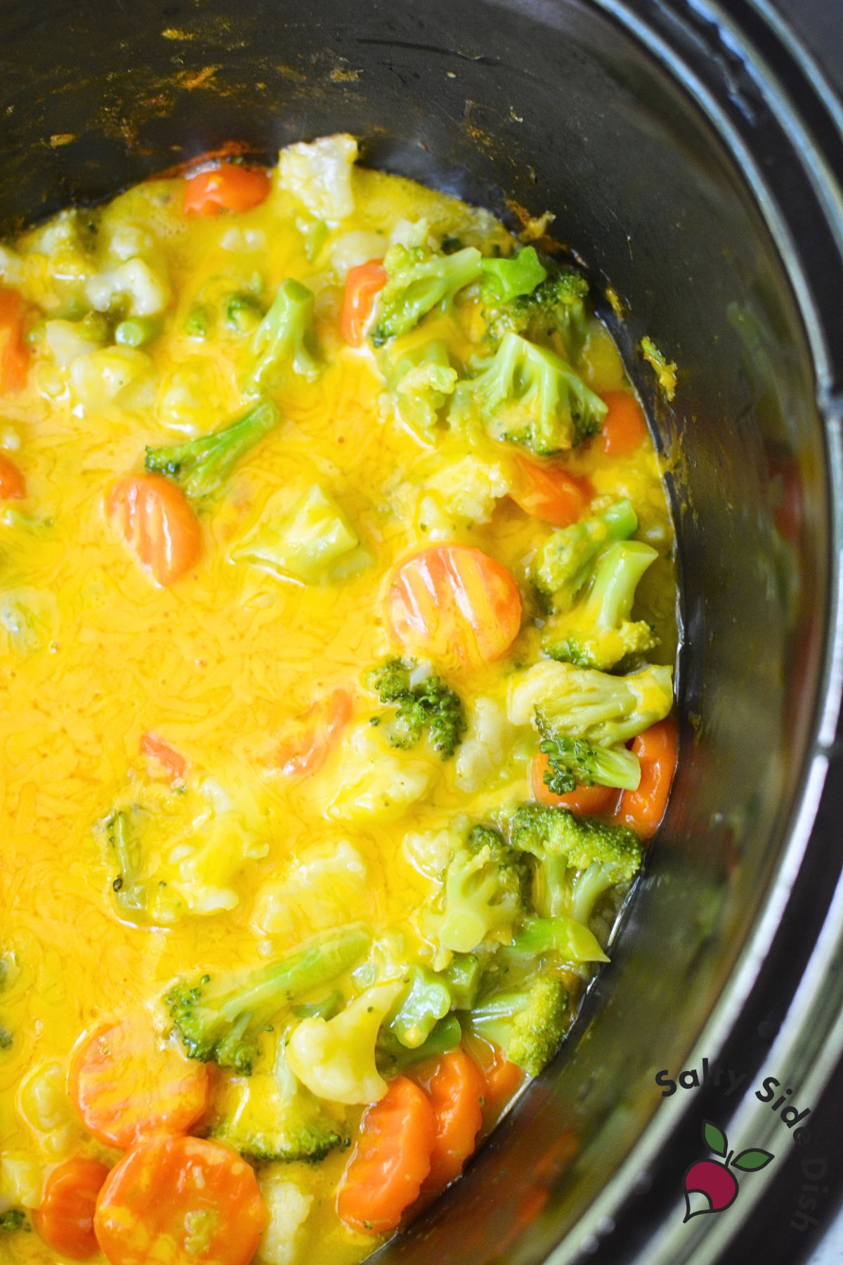Bowl of cheesy vegetables with broccoli, carrots, and cauliflower