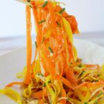 Overhead close-up of shaved carrot salad with sesame seeds and fresh chopped chives