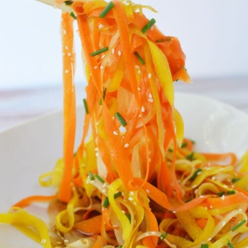 Overhead close-up of shaved carrot salad with sesame seeds and fresh chopped chives