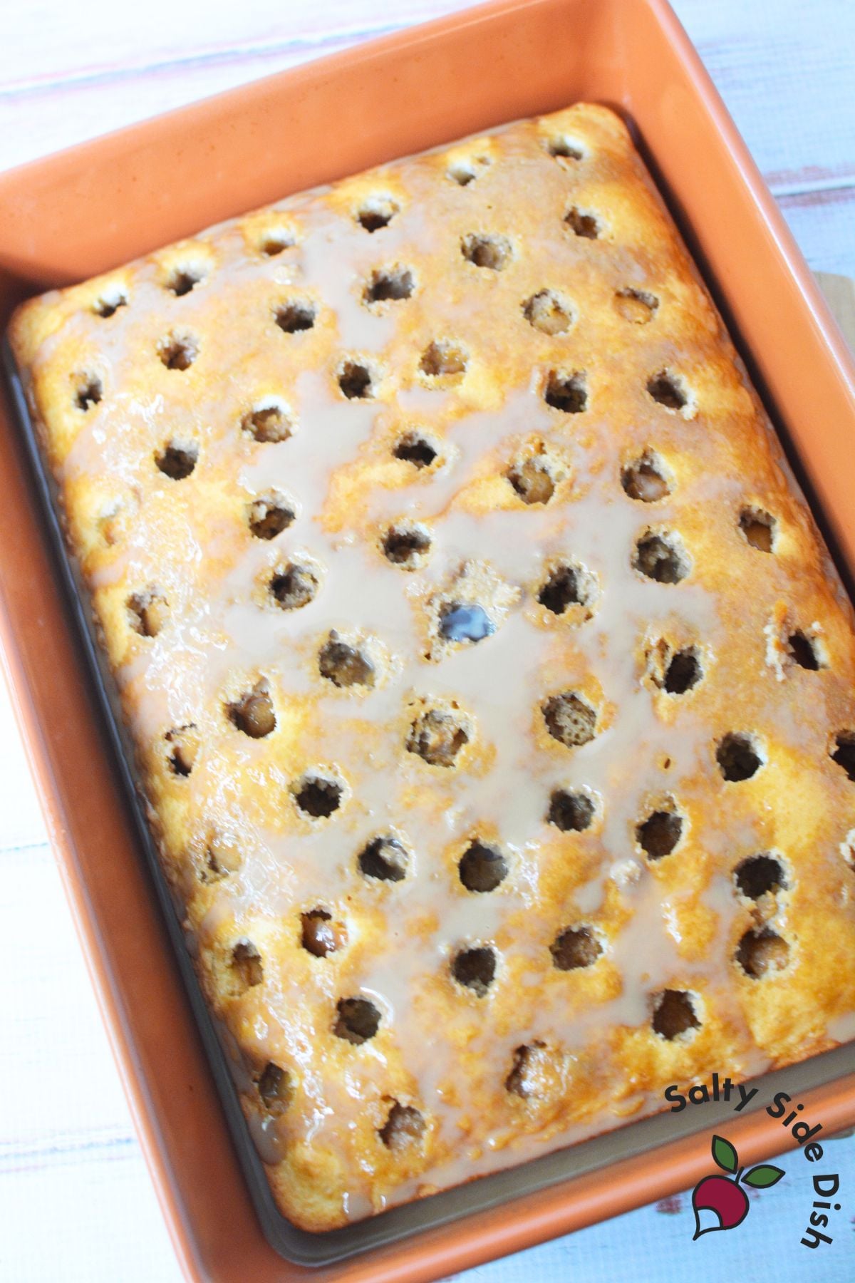 Freshly baked white cake with poke holes filled with coffee and condensed milk for tiramisu poke cake recipe.