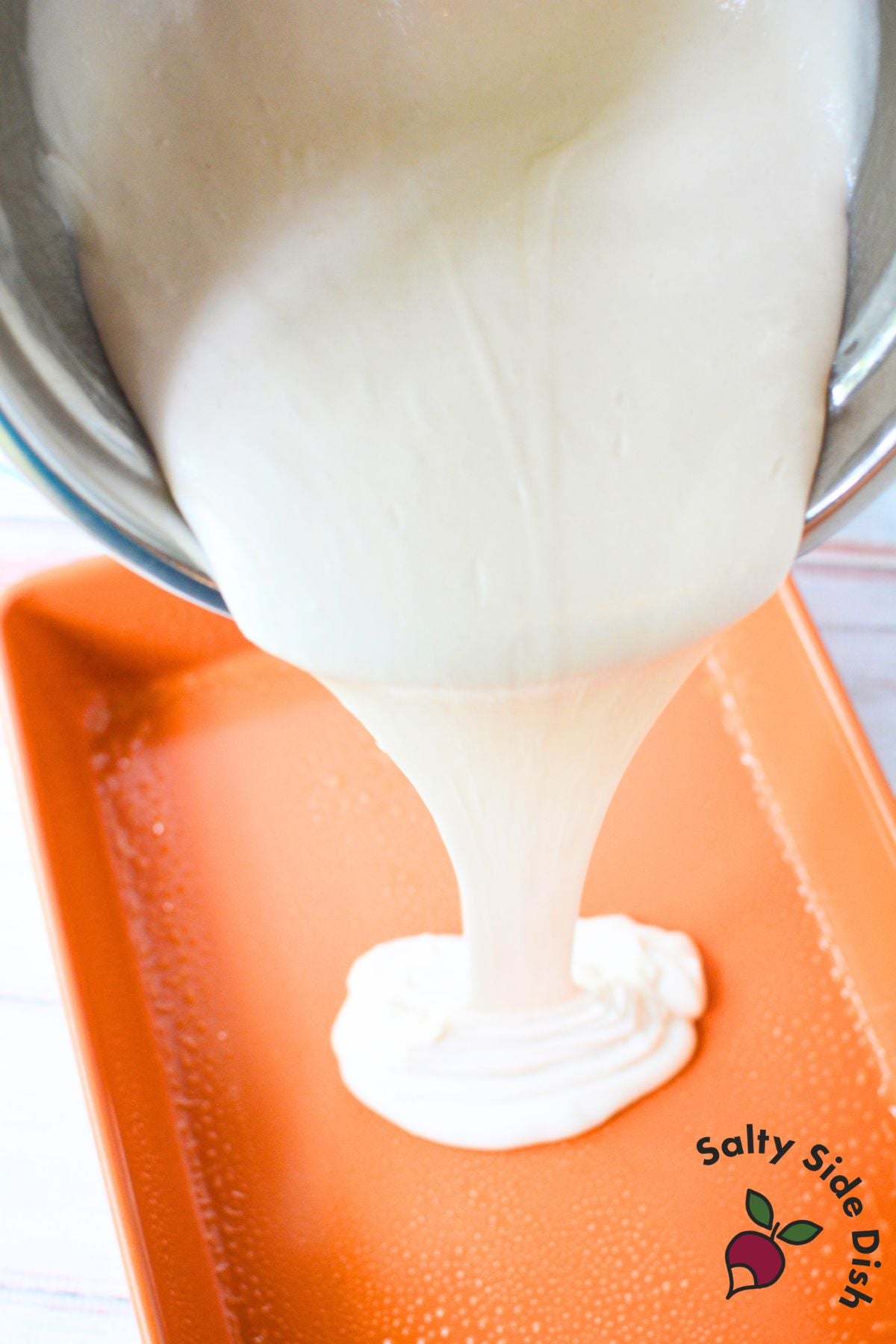 White cake batter being poured into a greased 9x13 pan to make easy tiramisu poke cake.