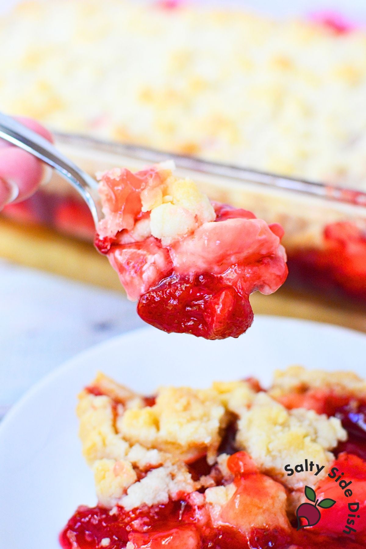 Spoonful of warm strawberry dump cake with gooey filling and cream cheese.
