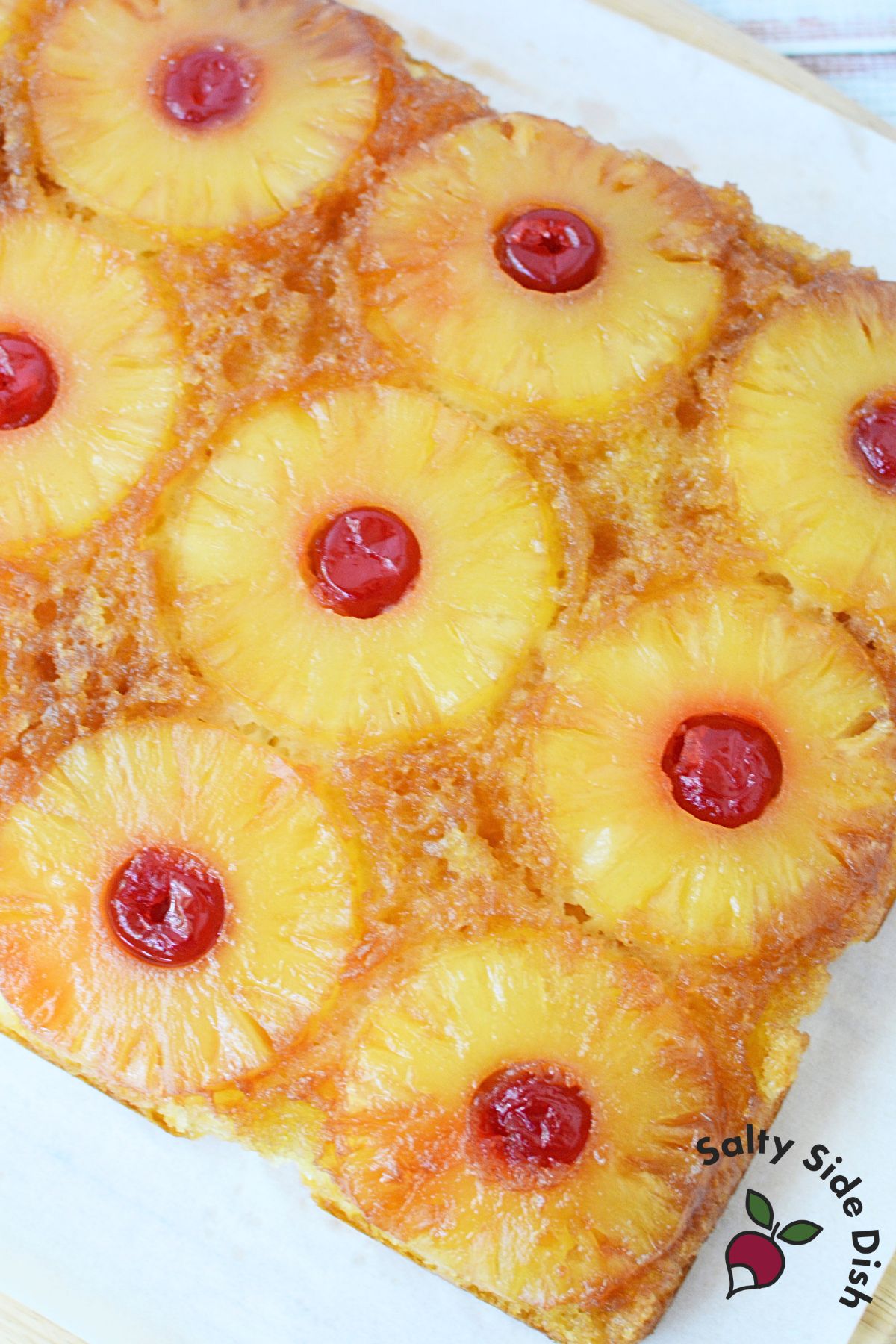 Close-up of pineapple upside down cake slices topped with pineapple rings and maraschino cherries.