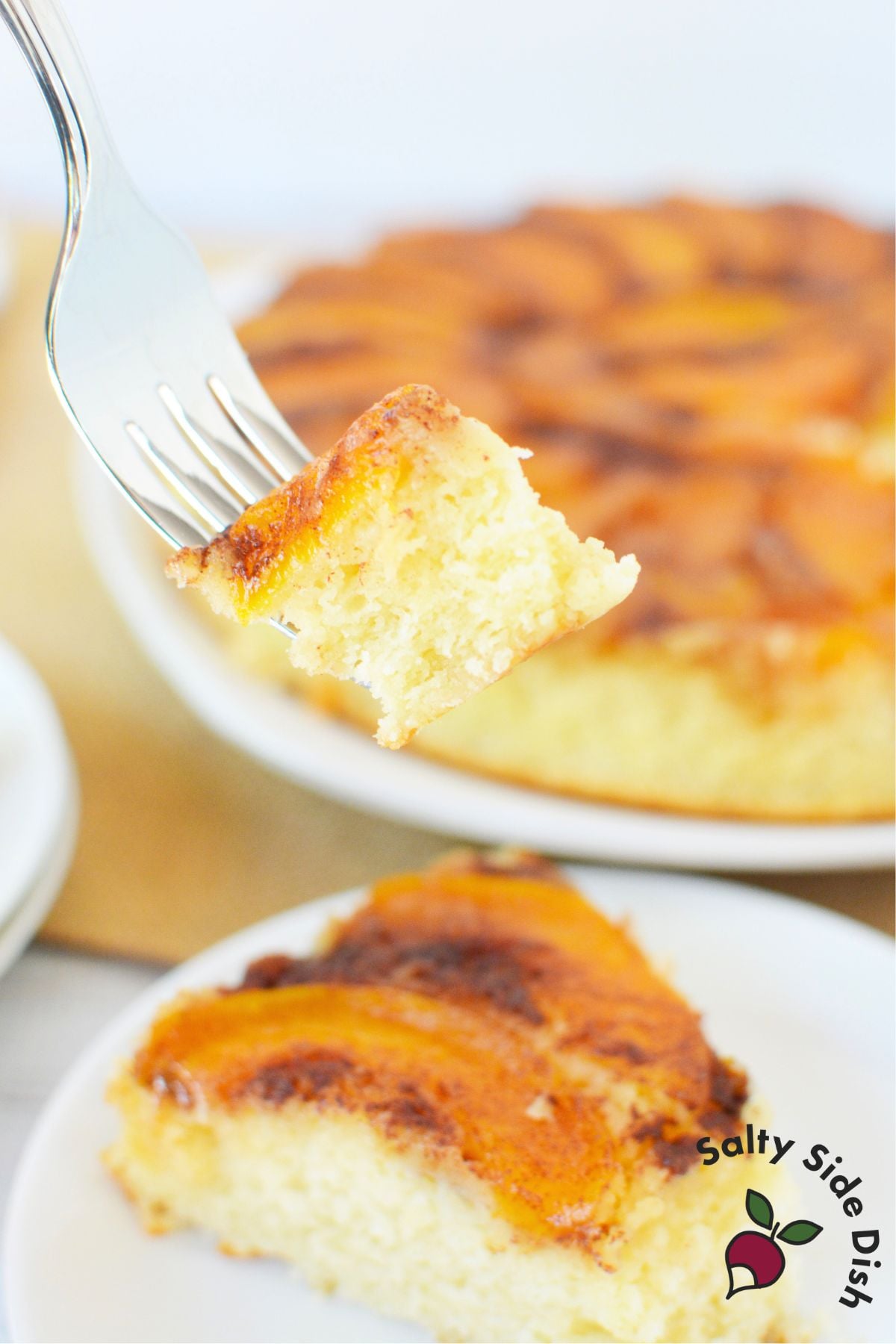 Utensil holding a bite of peach upside down cake with fluffy texture