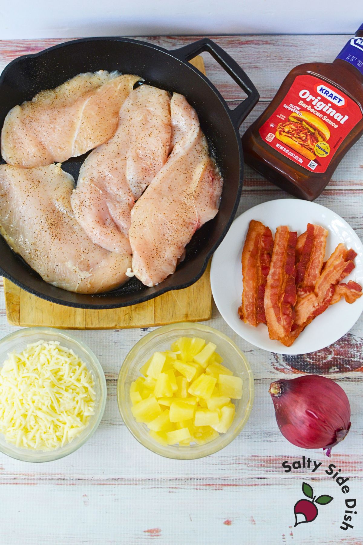 Ingredients for BBQ Hawaiian chicken including chicken breasts, barbecue sauce, pineapple, bacon, red onion, and cheese.