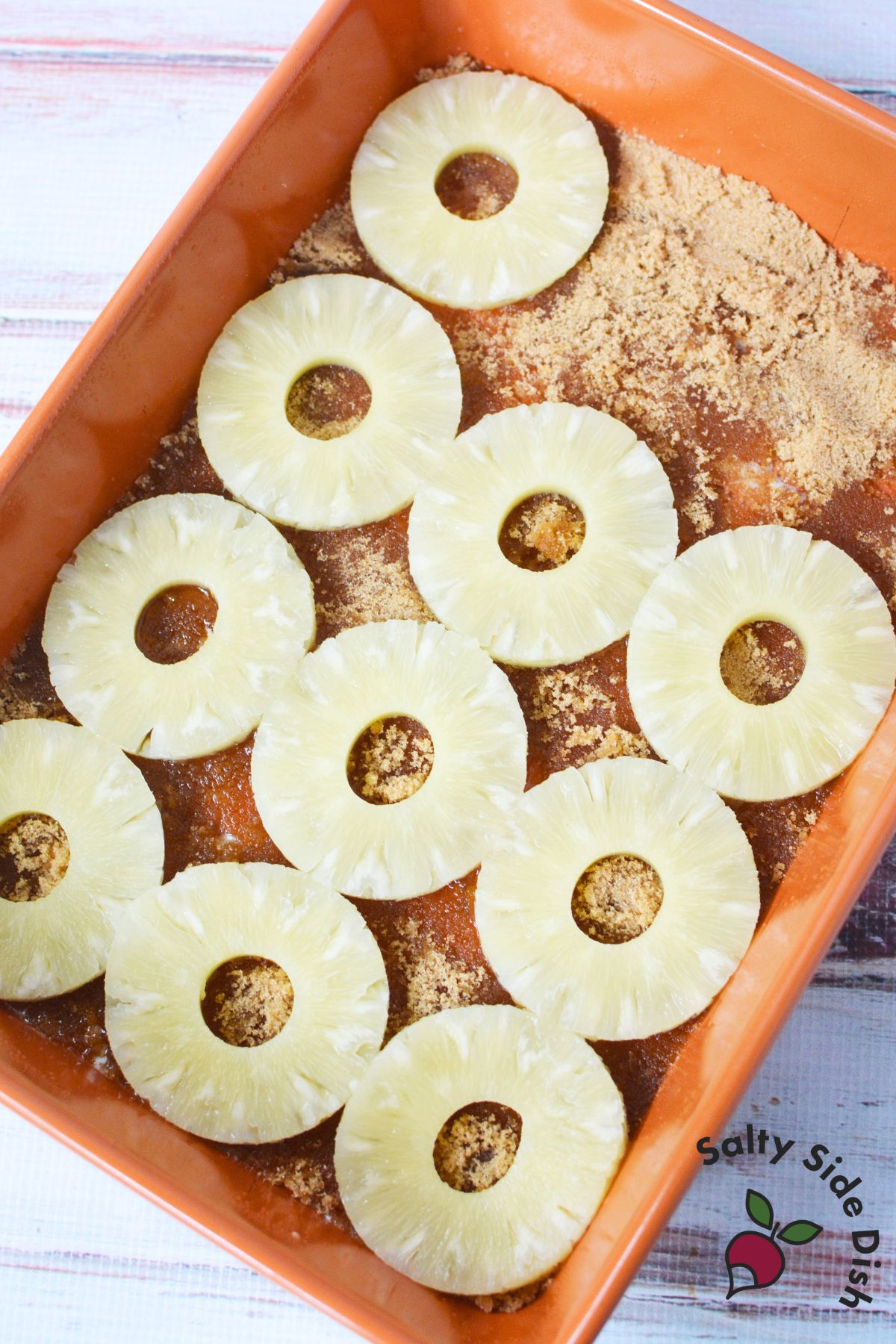 Pineapple rings arranged over brown sugar and melted butter in a 9x13 baking pan for pineapple upside down cake.