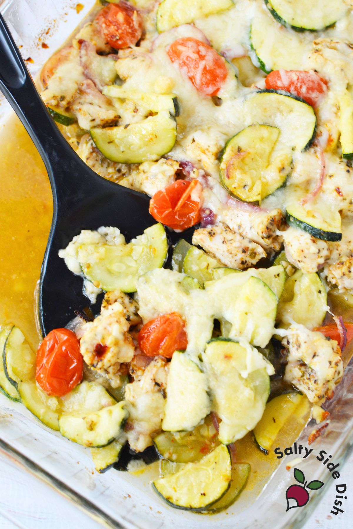 Close up of Mediterranean zucchini chicken bake with golden melted cheese and roasted tomatoes.