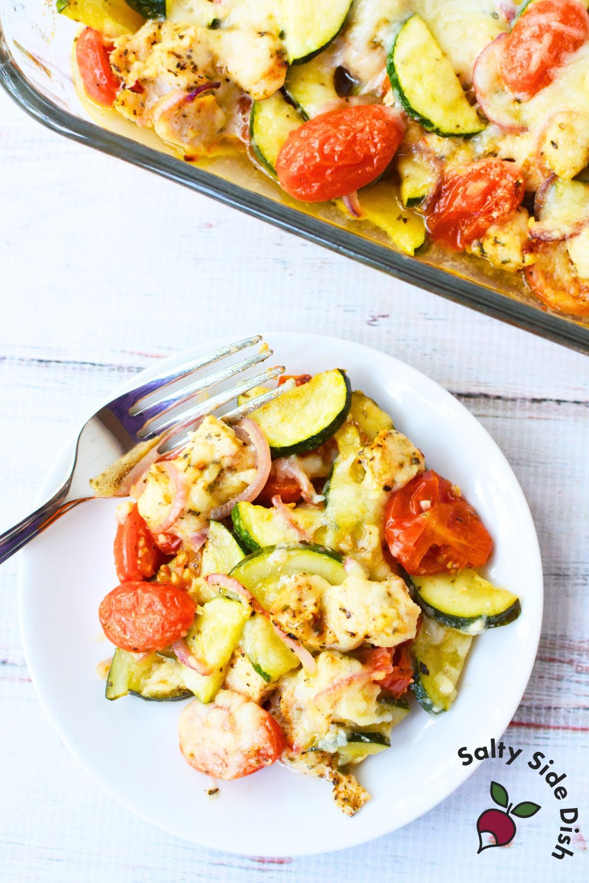 Plate of Mediterranean chicken bake with zucchini, tomatoes, and melted cheese.