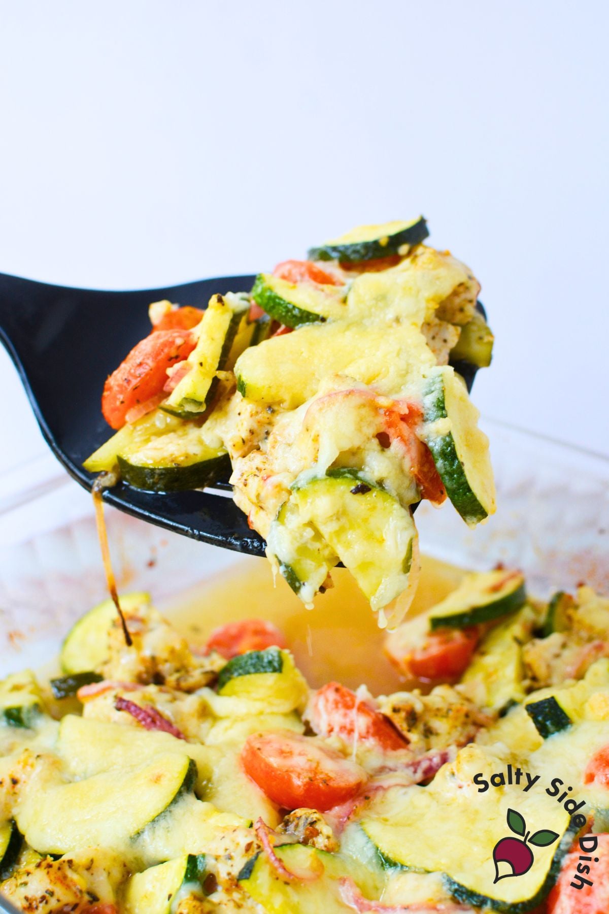 Spoonful of Mediterranean zucchini chicken bake with melted cheese and vegetables.