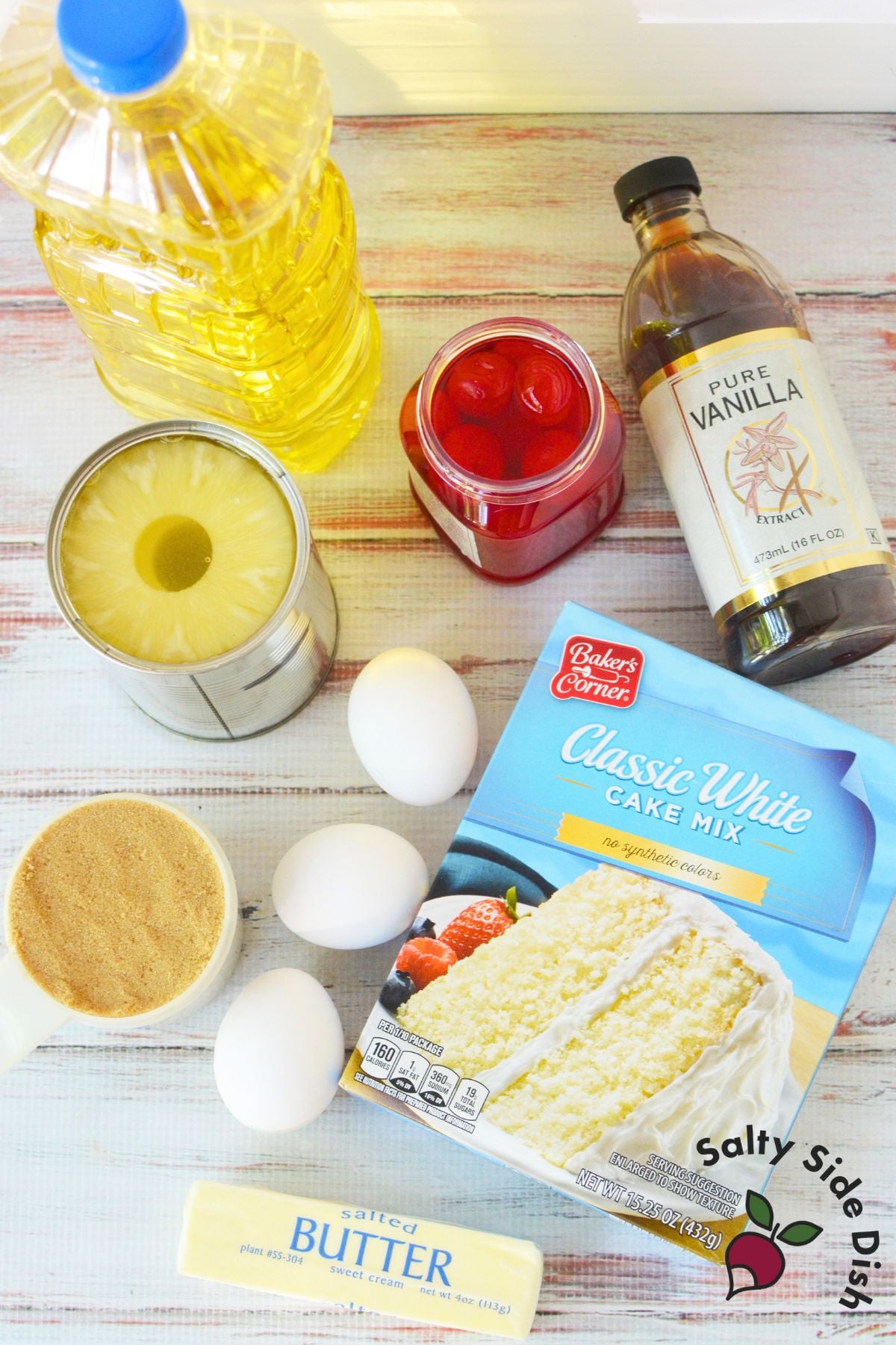 Ingredients for easy pineapple upside down cake including cake mix, pineapple slices, maraschino cherries, vanilla, eggs, oil, butter, and brown sugar.