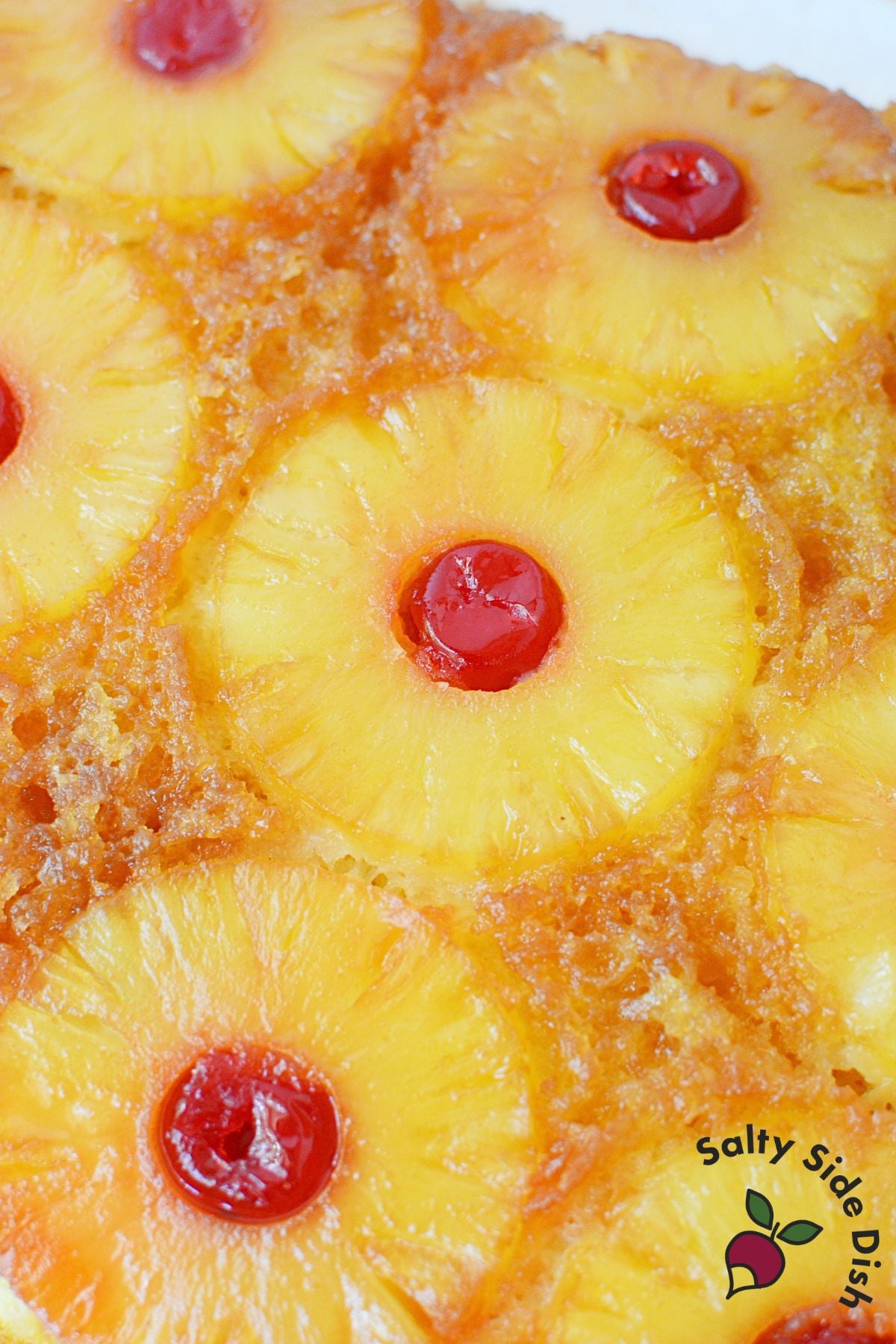 Freshly baked pineapple upside down cake flipped out of the pan with caramelized pineapple rings and cherries.