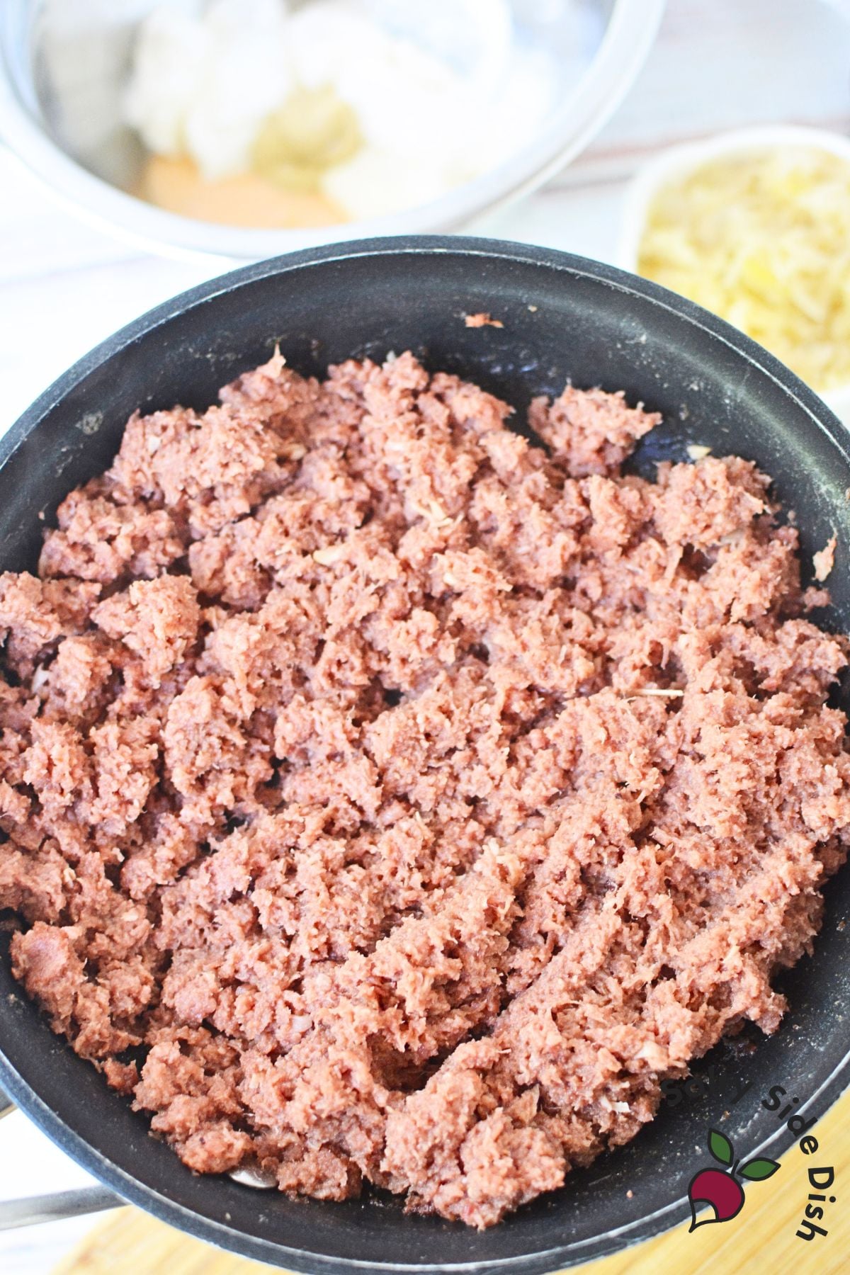 Canned corned beef being browned in a skillet before adding to pasta salad.