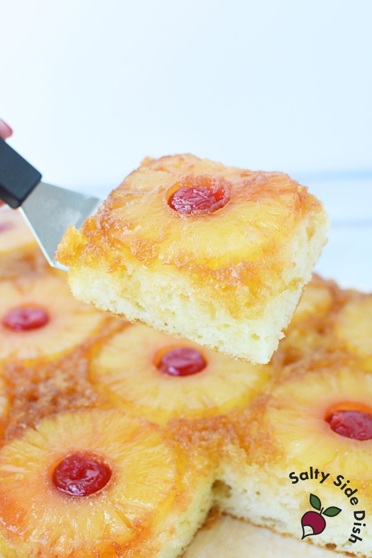 Close view of caramelized pineapple rings and bright red cherries on top of pineapple upside down cake.