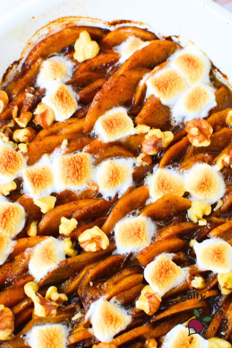 Scalloped sweet potatoes layered in a casserole dish with toasted marshmallows and walnuts