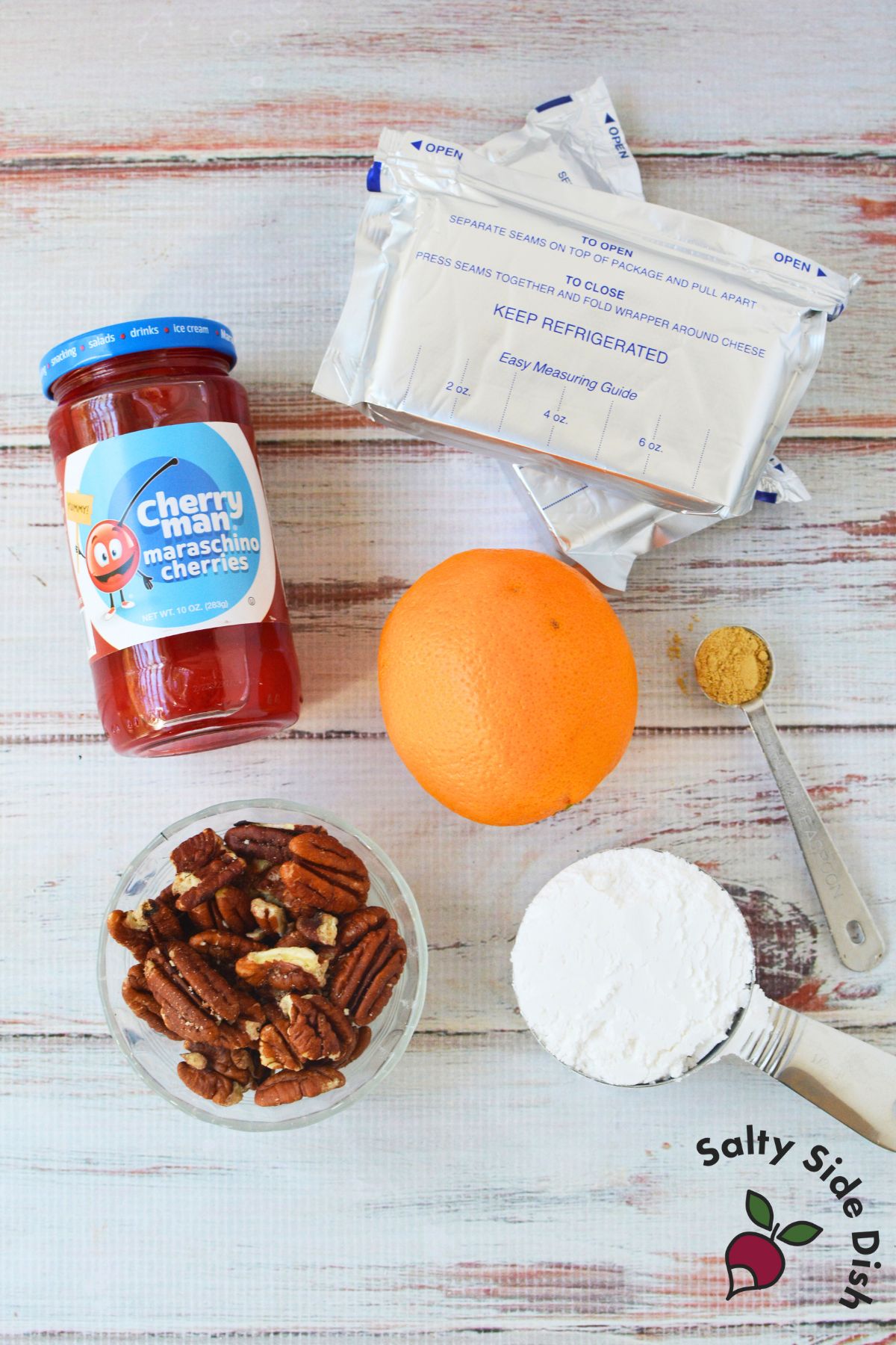 Ingredients for cherry cream cheese log including cream cheese, powdered sugar, maraschino cherries, orange, ginger, and pecans