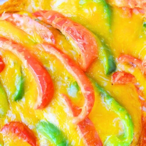 Baked chicken fajita casserole topped with melted cheddar cheese, red bell peppers, and green bell peppers