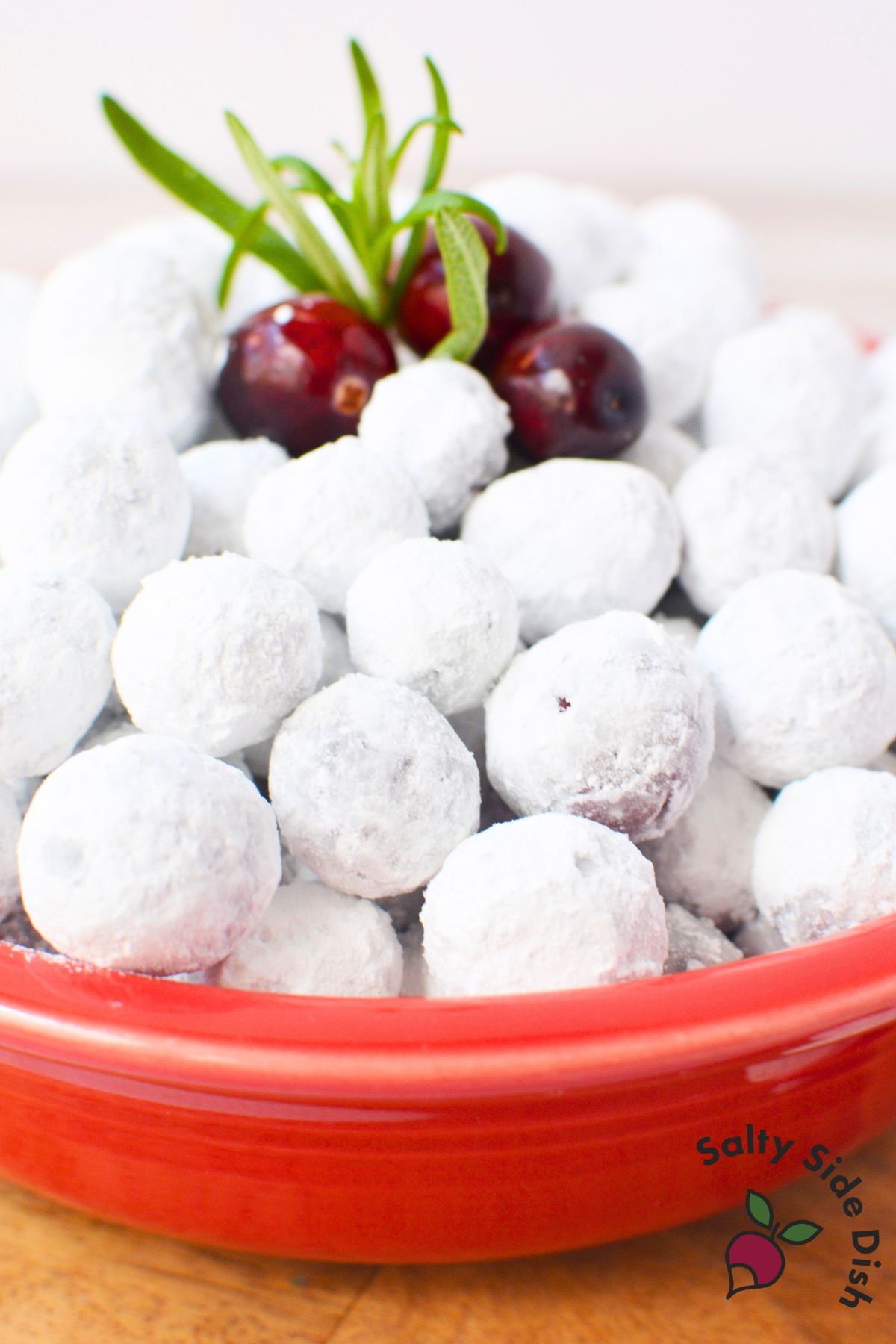Bowl of sugared cranberries with rosemary garnish, perfect for holiday cocktails or dessert topping.