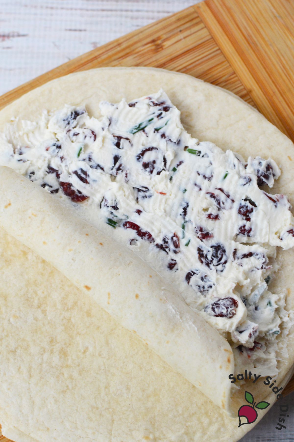 Cream cheese and cranberry filling spread over a flour tortilla before rolling.