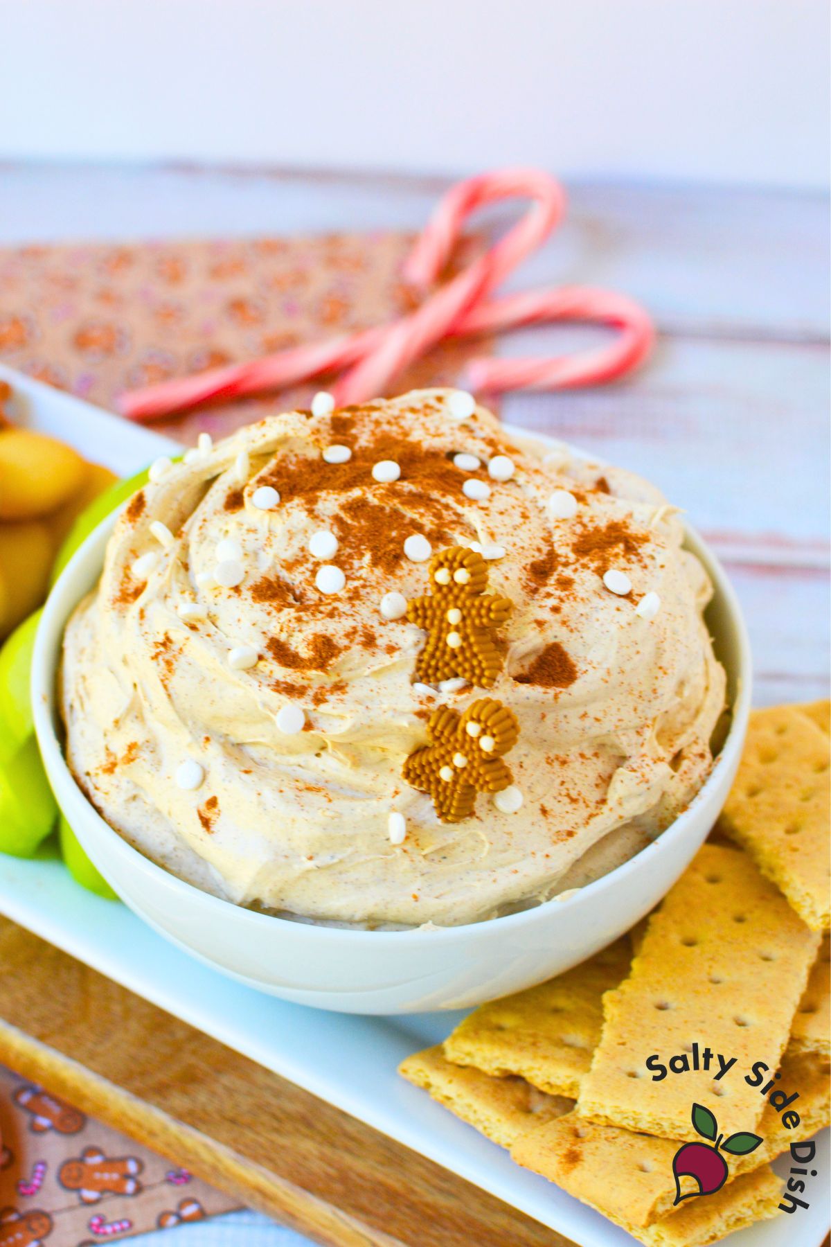 Close up of gingerbread dip topped with sprinkles and gingerbread men candies in a white serving bowl.
