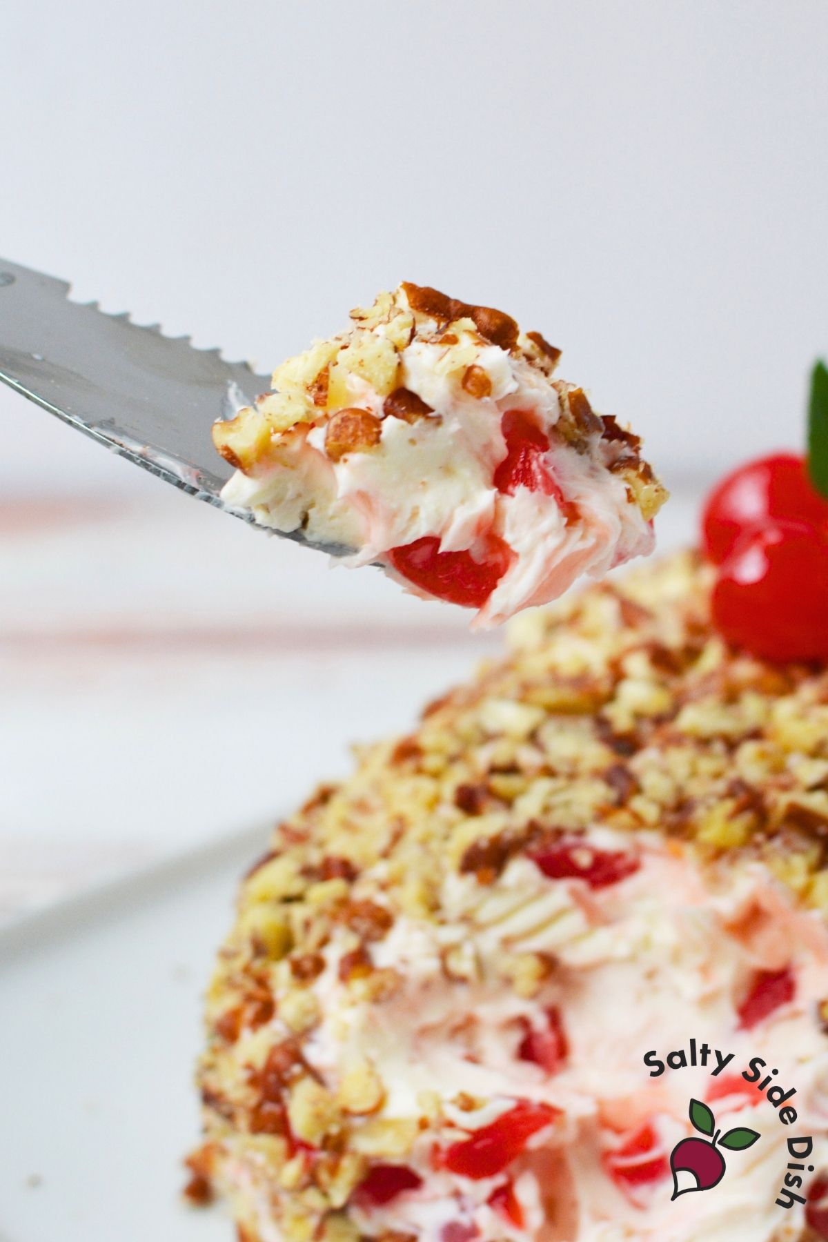 Knife lifting a piece of cherry cream cheese log with cherries and cream cheese filling
