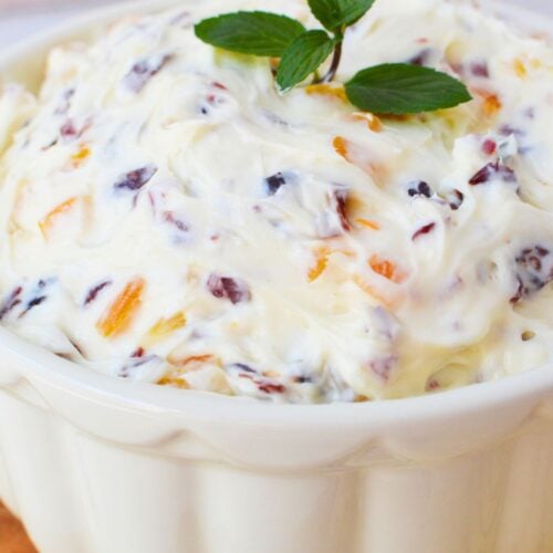 Creamy cranberry orange spread with fresh mint garnish in a white bowl for Christmas appetizers
