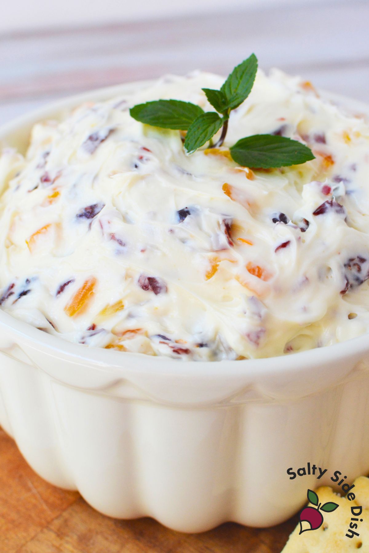 Creamy cranberry orange spread with fresh mint garnish in a white bowl for Christmas appetizers