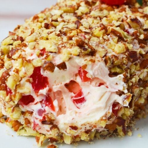 Festive cherry cream cheese log appetizer on a serving platter, topped with whole cherries and mint leaves