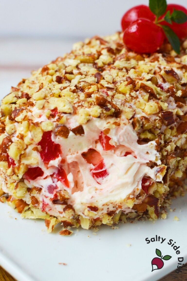 Festive cherry cream cheese log appetizer on a serving platter, topped with whole cherries and mint leaves