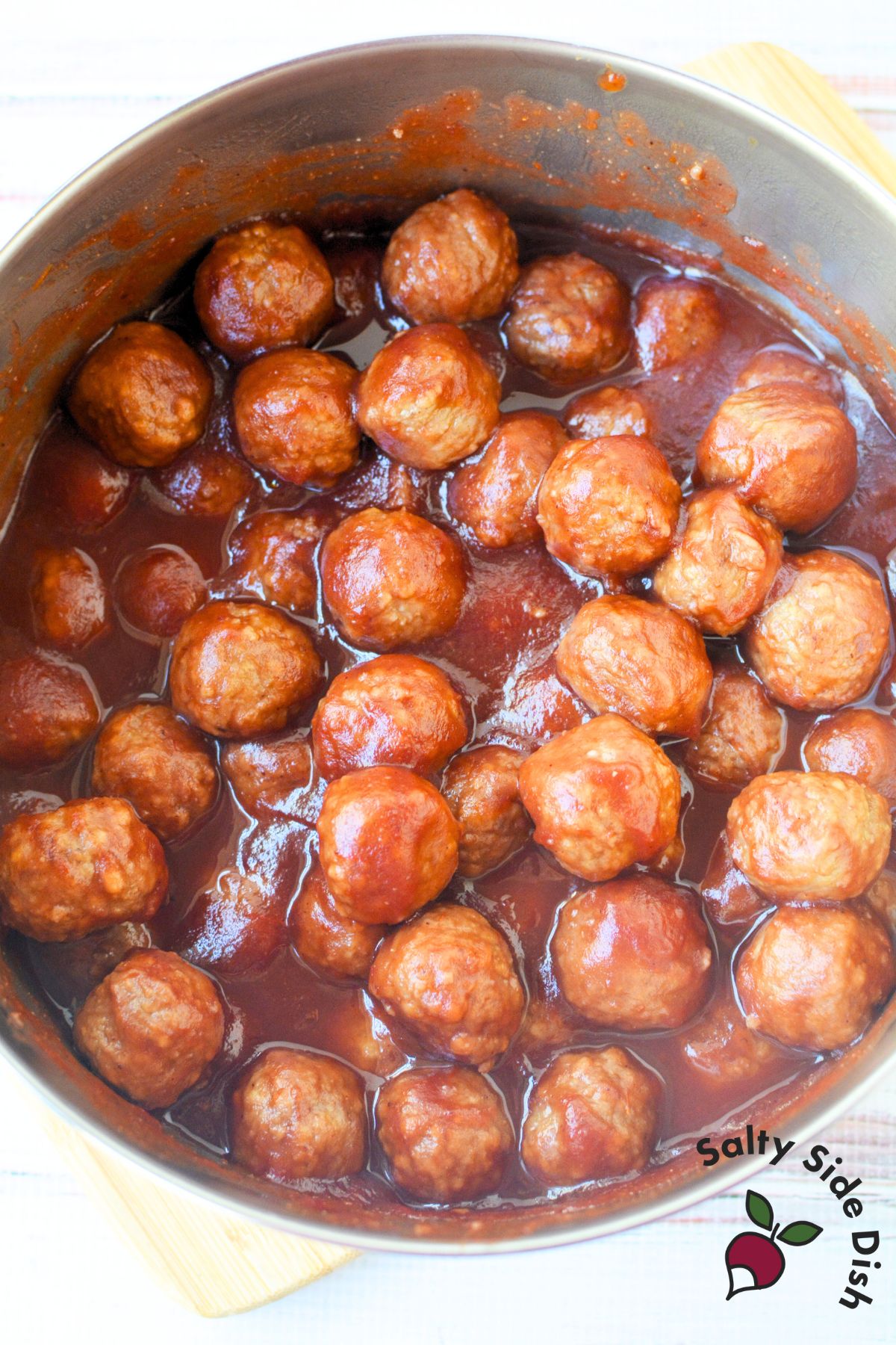 stovetop pot of meatballs in cranberry chili sauce simmering in glaze