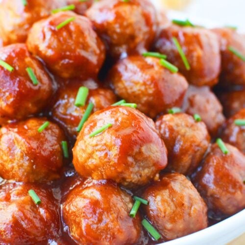 holiday appetizer meatballs with cranberry and chili sauce sprinkled with chives